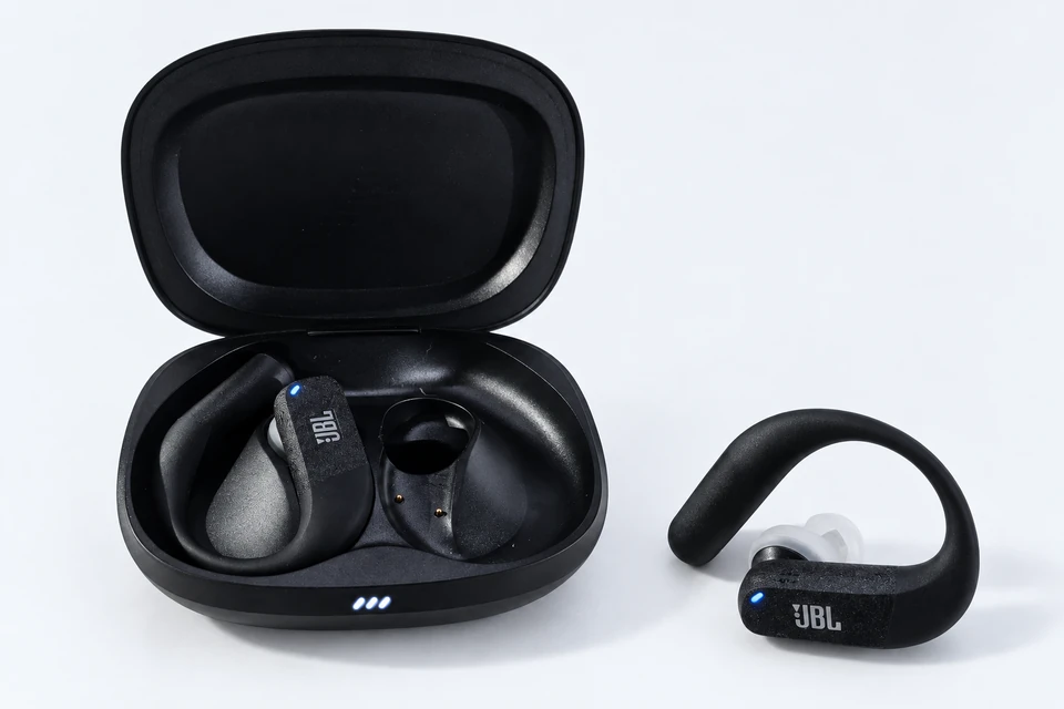Black JBL Endurance Peak 4 earbuds, one beside the open charging case showing its ear hook